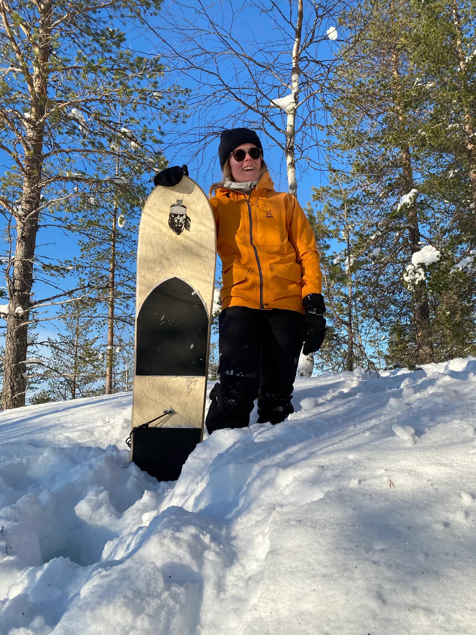 A guest holding a snow surfboard in a snowy forest